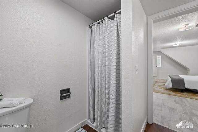 943 E 12th Ave # 6, Anchorage, AK 99501 - bathroom featuring a textured wall, toilet, a textured ceiling, wood finished floors, and baseboards
