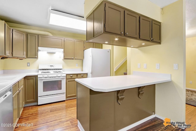 2003 Jamestown Cir, Anchorage, AK 99507 - kitchen with white appliances, under cabinet range hood, a peninsula, light wood finished floors, and light countertops
