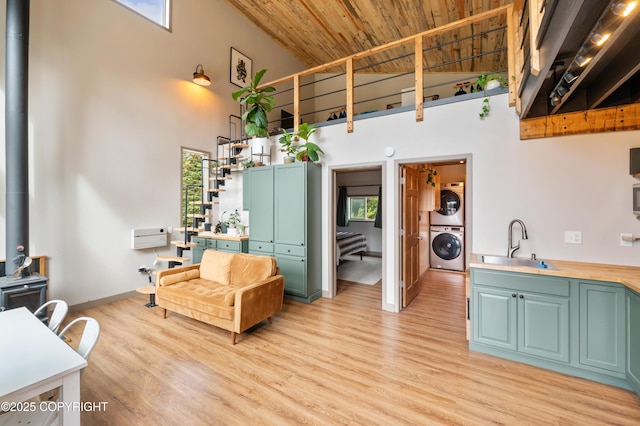 36339 Maria Rd, Homer, AK 99603 - living area featuring high vaulted ceiling, stacked washer / drying machine, wooden ceiling, light wood-style flooring, and a wood stove