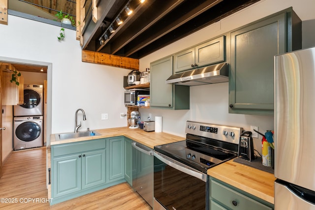 36339 Maria Rd, Homer, AK 99603 - kitchen with stainless steel appliances, estacked washer and dryer, under cabinet range hood, and butcher block counters