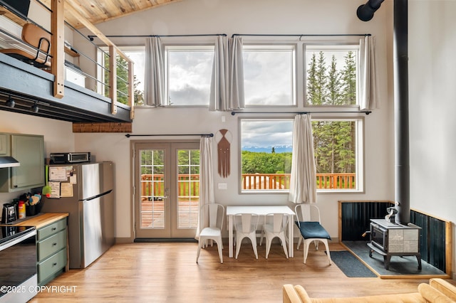 36339 Maria Rd, Homer, AK 99603 - kitchen featuring green cabinets, a wood stove, stainless steel appliances, high vaulted ceiling, and light wood finished floors