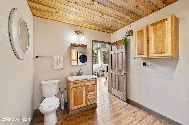 36339 Maria Rd, Homer, AK 99603 - bathroom featuring stacked washer / dryer, wooden ceiling, vanity, and wood finished floors