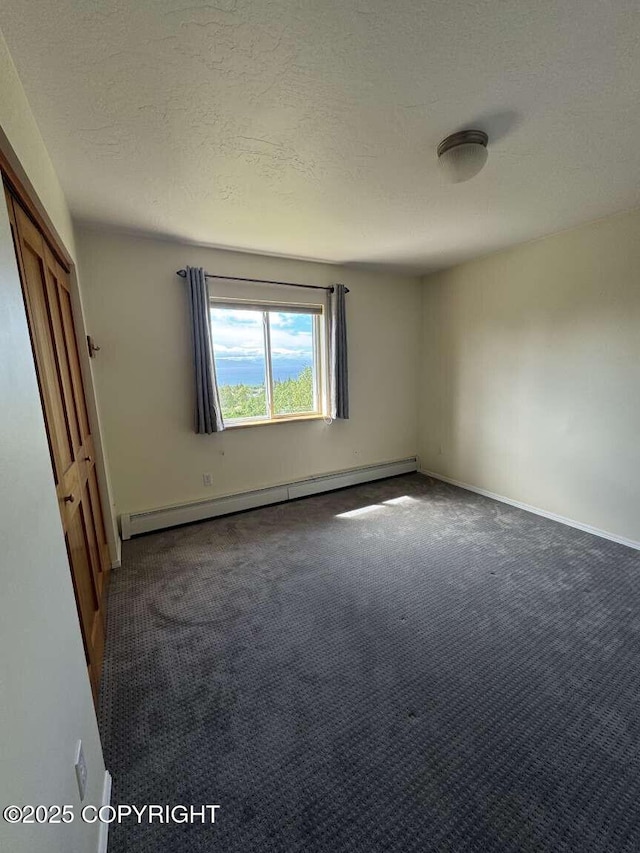 705 W Fairview Ave, Homer, AK 99603 - unfurnished bedroom featuring a baseboard radiator, carpet flooring, a textured ceiling, and baseboards