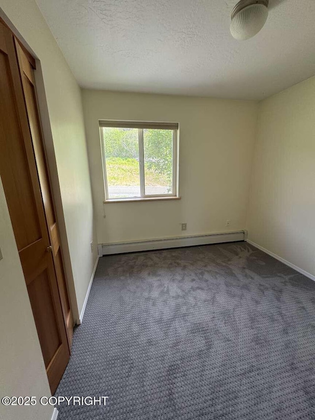 705 W Fairview Ave, Homer, AK 99603 - unfurnished bedroom with carpet floors, baseboards, a textured ceiling, and baseboard heating