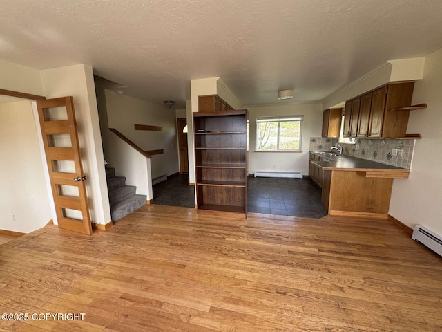 705 W Fairview Ave, Homer, AK 99603 - kitchen featuring stainless steel counters, open shelves, wood finished floors, a baseboard radiator, and backsplash