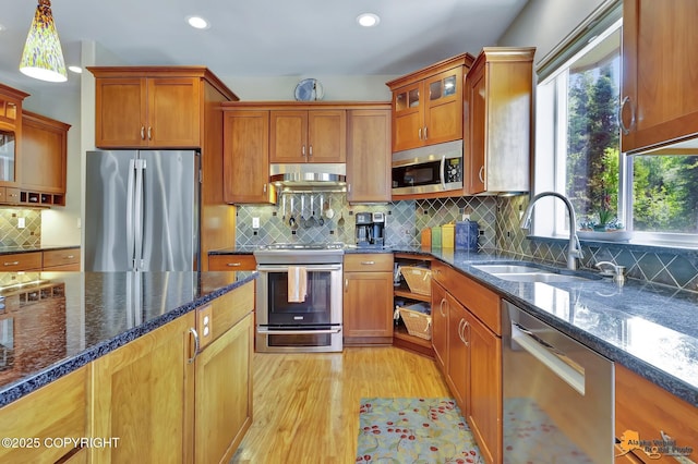 2842 Ensign Dr, Anchorage, AK 99515 - kitchen featuring appliances with stainless steel finishes, light wood-type flooring, under cabinet range hood, glass insert cabinets, and decorative backsplash