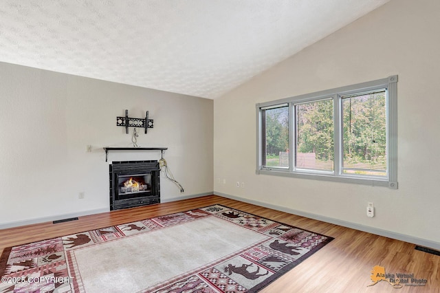 3091 N Longspur Dr, Wasilla, AK 99654 - unfurnished living room featuring wood finished floors, lofted ceiling, and a glass covered fireplace