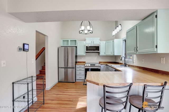 3091 N Longspur Dr, Wasilla, AK 99654 - kitchen with stainless steel appliances, a peninsula, light wood-style flooring, light countertops, and a kitchen breakfast bar