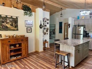 18905 Langille Rd, Cooper Landing, AK 99572 - kitchen featuring freestanding refrigerator, dark wood-type flooring, a breakfast bar, decorative light fixtures, and a center island