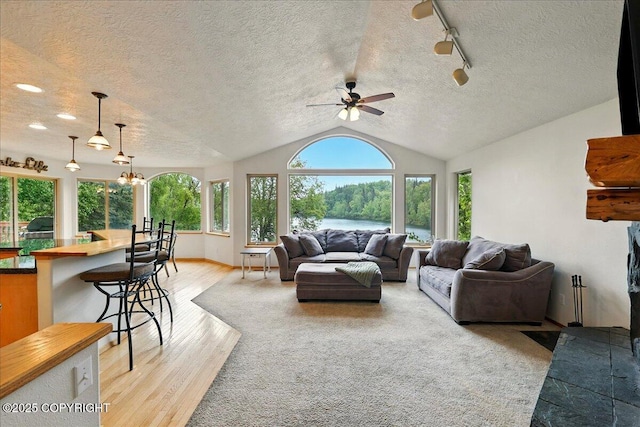 51137 Nanook Cir, Nikiski/North Kenai, AK 99611 - living area with a ceiling fan, light wood-style floors, a water view, lofted ceiling, and a textured ceiling