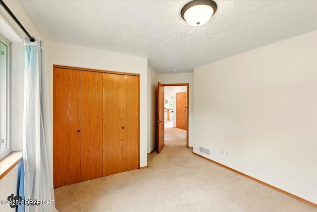 51137 Nanook Cir, Nikiski/North Kenai, AK 99611 - unfurnished bedroom featuring light colored carpet, a closet, a textured ceiling, and baseboards