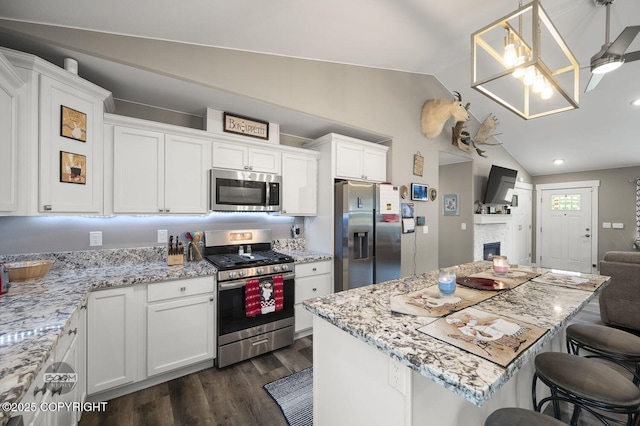 1169 W Trumpeter Swan Dr, Wasilla, AK 99623 - kitchen featuring appliances with stainless steel finishes, vaulted ceiling, open floor plan, white cabinetry, and dark wood finished floors
