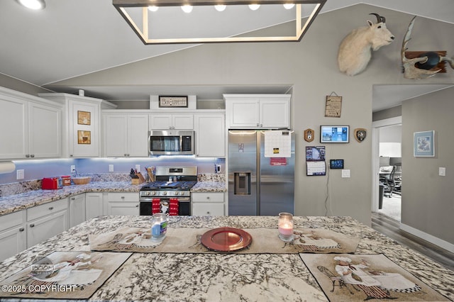1169 W Trumpeter Swan Dr, Wasilla, AK 99623 - kitchen featuring appliances with stainless steel finishes, lofted ceiling, white cabinetry, and light stone countertops