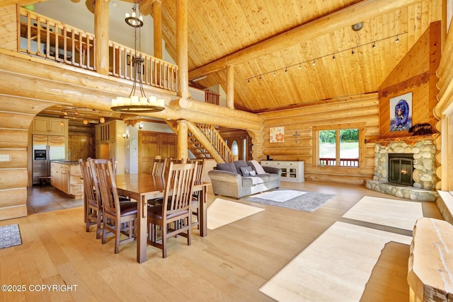 3108 Misty Mountain Rd, Eagle River, AK 99577 - dining area featuring log walls, a wood ceiling with exposed beams, high vaulted ceiling, light wood-style flooring, and a stone fireplace
