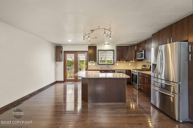 10010 Colville St, Eagle River, AK 99577 - kitchen featuring stainless steel appliances, dark brown cabinetry, a center island, tasteful backsplash, and dark wood finished floors