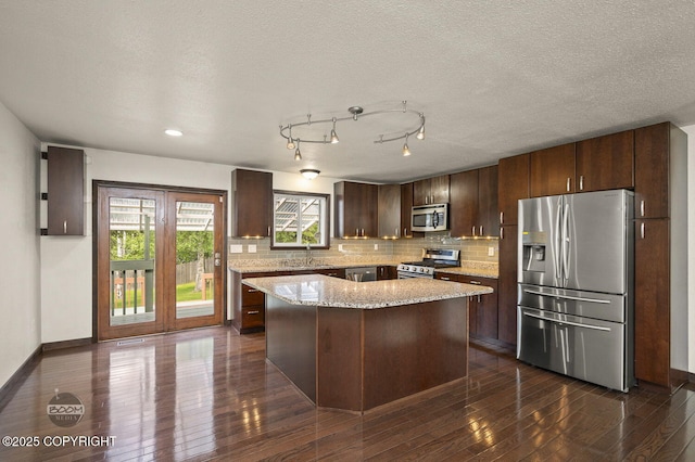 10010 Colville St, Eagle River, AK 99577 - kitchen featuring stainless steel appliances, backsplash, dark brown cabinets, dark wood finished floors, and light stone countertops