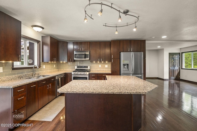 10010 Colville St, Eagle River, AK 99577 - kitchen with appliances with stainless steel finishes, a kitchen island, decorative backsplash, and light stone countertops