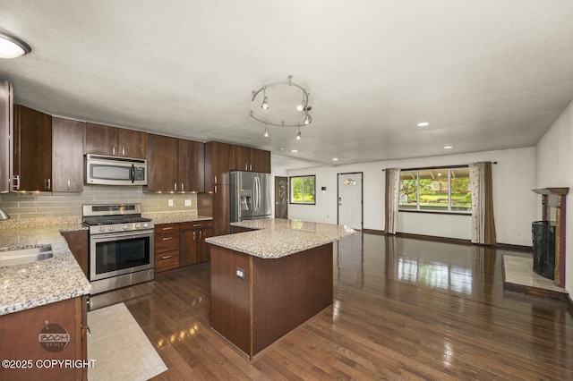10010 Colville St, Eagle River, AK 99577 - kitchen featuring stainless steel appliances, a kitchen island, tasteful backsplash, dark wood finished floors, and light stone counters
