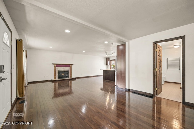10010 Colville St, Eagle River, AK 99577 - unfurnished living room with dark wood-style flooring, a warm lit fireplace, and recessed lighting