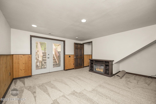 10010 Colville St, Eagle River, AK 99577 - unfurnished living room with wood walls, carpet, french doors, wainscoting, and a glass covered fireplace