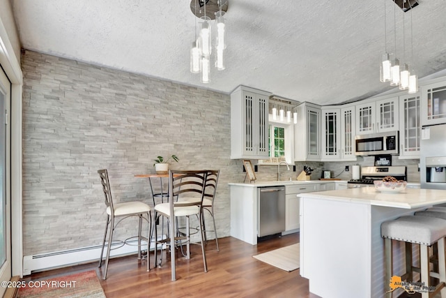 2309 Success Dr, Anchorage, AK 99504 - kitchen featuring appliances with stainless steel finishes, a breakfast bar area, a textured ceiling, dark wood-style floors, and light countertops