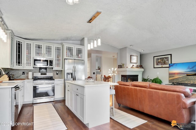 2309 Success Dr, Anchorage, AK 99504 - kitchen with appliances with stainless steel finishes, a textured ceiling, open floor plan, dark wood-type flooring, and tasteful backsplash