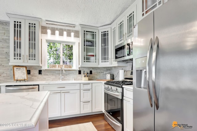 2309 Success Dr, Anchorage, AK 99504 - kitchen featuring stainless steel appliances, backsplash, dark wood finished floors, a textured ceiling, and glass insert cabinets