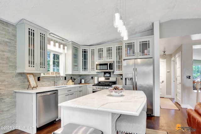 2309 Success Dr, Anchorage, AK 99504 - kitchen with stainless steel appliances, lofted ceiling, dark wood-style floors, tasteful backsplash, and a center island
