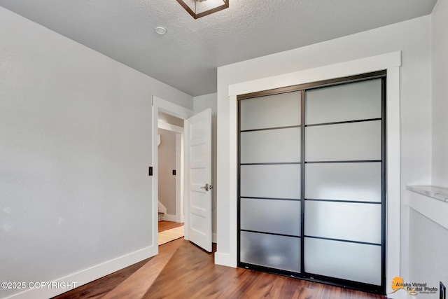 2309 Success Dr, Anchorage, AK 99504 - unfurnished bedroom featuring wood finished floors, a closet, and a textured ceiling