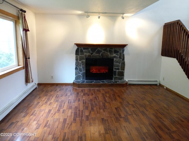 17701 Beaujolais Dr, Eagle River, AK 99577 - unfurnished living room featuring baseboard heating, track lighting, wood finished floors, and a stone fireplace