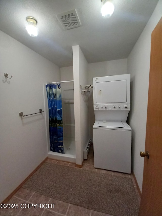 17701 Beaujolais Dr, Eagle River, AK 99577 - laundry area featuring stacked washer and clothes dryer, a baseboard heating unit, and tile patterned floors