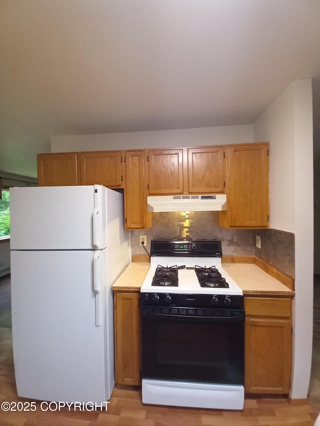 17701 Beaujolais Dr, Eagle River, AK 99577 - kitchen featuring gas range, freestanding refrigerator, under cabinet range hood, light countertops, and tasteful backsplash