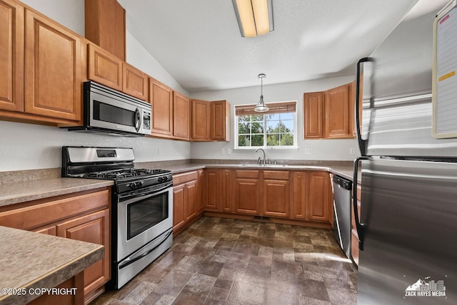 7595 E Breckenridge Dr, Wasilla, AK 99654 - kitchen with stainless steel appliances, brown cabinetry, vaulted ceiling, pendant lighting, and stone finish floors