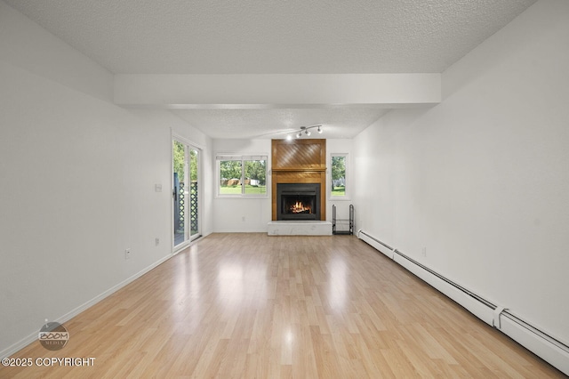 1675 Sitka St # 102, Anchorage, AK 99501 - unfurnished living room featuring baseboard heating, light wood-style floors, a large fireplace, and a textured ceiling