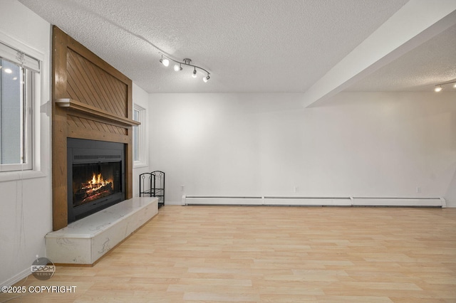 1675 Sitka St # 102, Anchorage, AK 99501 - unfurnished living room featuring a textured ceiling, a large fireplace, light wood-style flooring, and a baseboard radiator