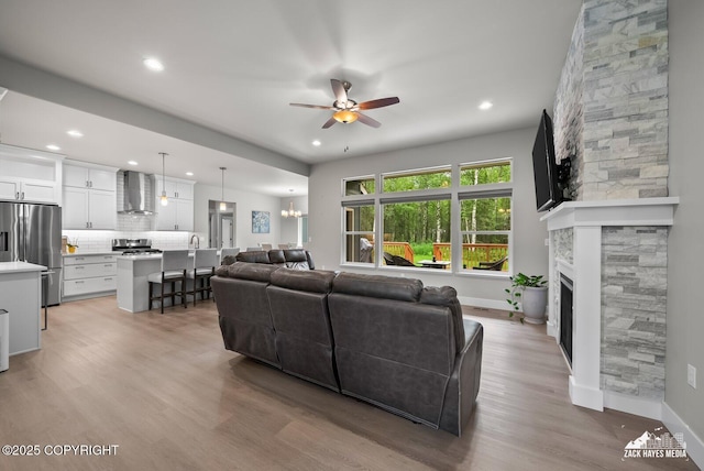 8028 E Yarn Spinner Cir, Palmer, AK 99645 - living area featuring a ceiling fan, recessed lighting, light wood finished floors, a fireplace, and a chandelier