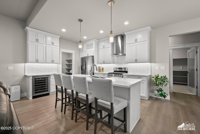 8028 E Yarn Spinner Cir, Palmer, AK 99645 - kitchen featuring wall chimney range hood, beverage cooler, appliances with stainless steel finishes, light countertops, and a kitchen bar