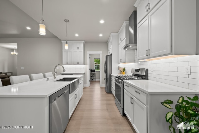 8028 E Yarn Spinner Cir, Palmer, AK 99645 - kitchen featuring stainless steel appliances, wall chimney range hood, recessed lighting, tasteful backsplash, and light wood-style floors