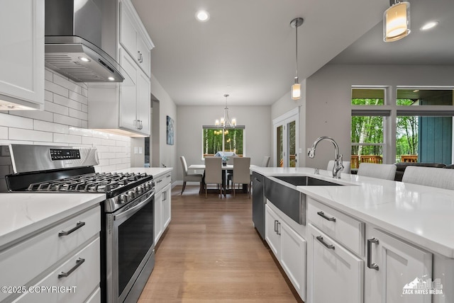 8028 E Yarn Spinner Cir, Palmer, AK 99645 - kitchen featuring appliances with stainless steel finishes, wall chimney exhaust hood, decorative backsplash, light wood-style flooring, and white cabinets