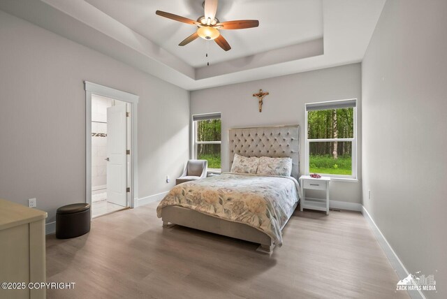 8028 E Yarn Spinner Cir, Palmer, AK 99645 - bedroom featuring wood finished floors, multiple windows, a tray ceiling, and ensuite bath