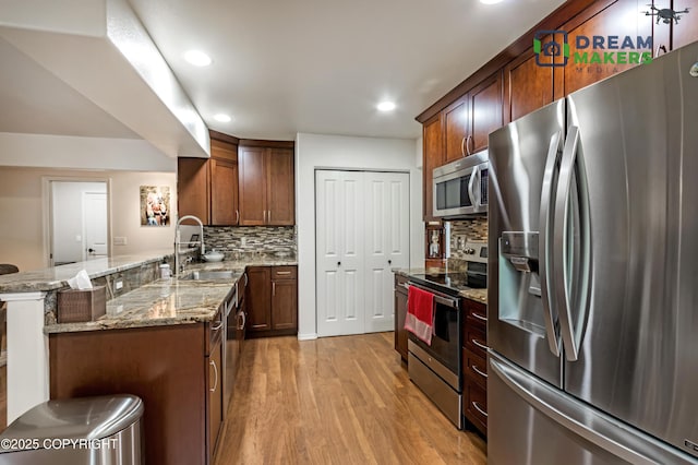 11240 E Equestrian St, Palmer, AK 99645 - kitchen featuring stainless steel appliances, a peninsula, light wood finished floors, recessed lighting, and light stone countertops