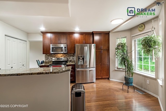 11240 E Equestrian St, Palmer, AK 99645 - kitchen featuring stainless steel appliances, decorative backsplash, light wood finished floors, dark stone counters, and recessed lighting