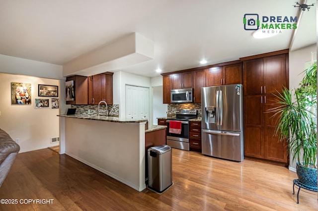 11240 E Equestrian St, Palmer, AK 99645 - kitchen with stainless steel appliances, light stone counters, light wood-type flooring, tasteful backsplash, and recessed lighting