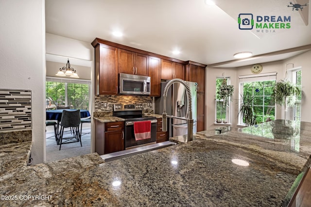 11240 E Equestrian St, Palmer, AK 99645 - kitchen with stainless steel appliances, backsplash, dark stone countertops, and a chandelier