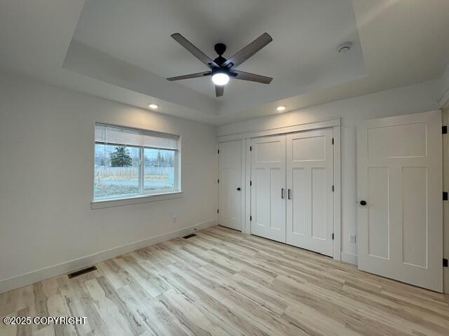 2033 E Chickaloon Rd, Wasilla, AK 99654 - unfurnished bedroom featuring a tray ceiling, light wood-style flooring, recessed lighting, a closet, and a ceiling fan