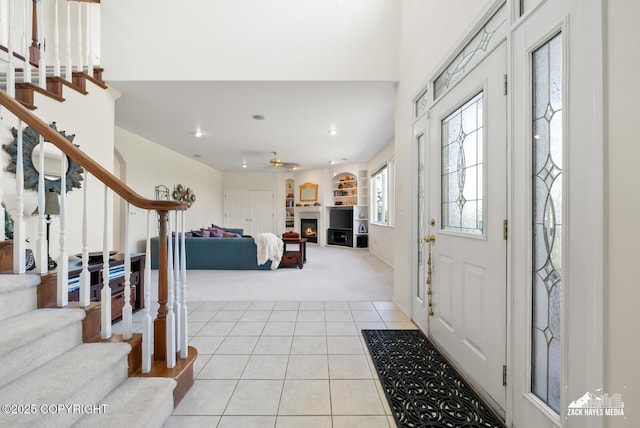 10100 Zermatt Cir, Anchorage, AK 99507 - entryway featuring light colored carpet, stairs, a warm lit fireplace, light tile patterned flooring, and recessed lighting