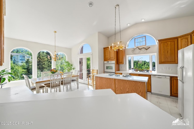 10100 Zermatt Cir, Anchorage, AK 99507 - kitchen with white appliances, a chandelier, high vaulted ceiling, light countertops, and hanging light fixtures