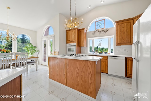 10100 Zermatt Cir, Anchorage, AK 99507 - kitchen with white appliances, a chandelier, light countertops, high vaulted ceiling, and hanging light fixtures