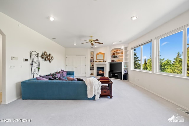 10100 Zermatt Cir, Anchorage, AK 99507 - carpeted living area with a ceiling fan, a glass covered fireplace, recessed lighting, built in shelves, and arched walkways