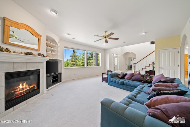 10100 Zermatt Cir, Anchorage, AK 99507 - living area featuring carpet flooring, arched walkways, a ceiling fan, a tile fireplace, and stairs